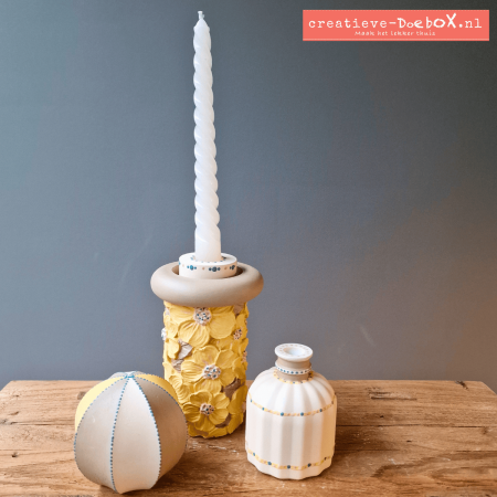 Voorbeeld Met aandacht in zachte lentekleuren: gele bloemen-cilinder met kaars, vaasje met stipdetails en ornament in wit en geel