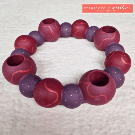 Hoe ziet een zelfgemaakte adventdecoratie eruit? Bekijk dit voorbeeld van een beschilderde adventring in warme kerstkleuren, inclusief kaarsen.